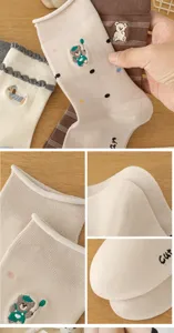 Close-up detail shot of cute cartoon embroidered cotton mid-calf socks with ribbed cuffs.