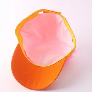 Detailed view of the funny baseball cap with pink wig hair and orange brim, interior lining.