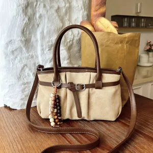 Vista dettagliata della borsa a tracolla retro in camoscio cachi con manici marroni e perle.