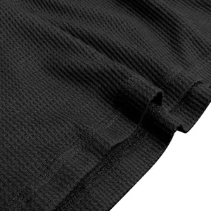 Close-up detail of black waffle knit fabric showing fine texture and neat hem stitching.