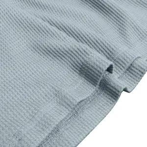 Fabric detail view of men's long sleeve henley shirt, soft ribbed knit texture in light blue.