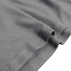 Grey waffle knit fabric detail closeup of men's long sleeve henley shirt, soft texture.
