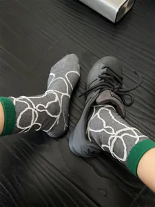 Gros plan détaillé de chaussettes grises mi-mollet avec lignes blanches et bordures vertes.