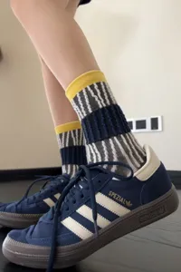 Gros plan détail de chaussettes mi-hautes rayées tendance avec revers jaunes, style urbain.
