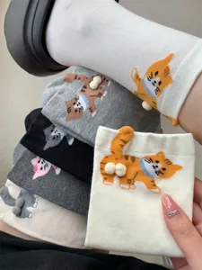 Close-up detail of cute 3d cat pom-pom socks, funny kitten design, soft cotton fabric.
