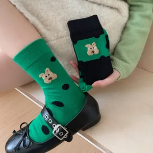 Primo piano di calzini verdi a pois a metà polpaccio con ricamo di orsetto carino.