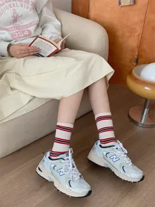 Scatto dettagliato di calzini a metà polpaccio a righe a contrasto abbinati a sneaker.