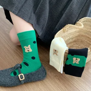 Primo piano dei calzini verdi a pois con un grazioso orsetto nel cestino di vimini.