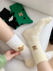 Dettaglio di calzini a pois a metà polpiscio con adorabile ricamo di orsetto cartoon.