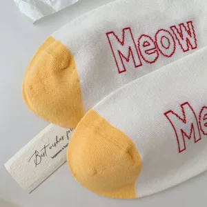 Cute cotton socks detail featuring yellow toe caps and playful red Meow letter embroidery.