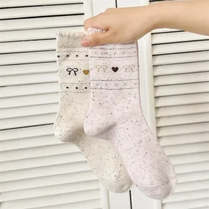Detail shot of vintage style women socks with cute bow and heart knit patterns in pink and beige.