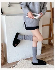 Grey knit leg warmers paired with black fluffy slippers, cozy Y2K style winter fashion.
