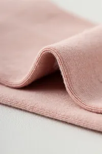 Rosa Strickstoff Detail Nahaufnahme mit weicher Textur und sauberer Kantenverarbeitung.