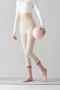 Nahaufnahme von Damen Yoga Socken in Rosa kombiniert mit beigen Leggings im Studio.