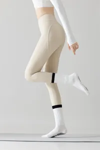 Nahaufnahme von Damen-Yogasocken mit Anti-Rutsch-Sohle und Sportleggings im Fotostudio.