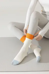 Vue détaillée de chaussettes de yoga pour femmes avec poignets orange pour le fitness en salle.