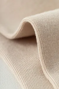 Detailed close-up shot of soft beige knitted fabric texture for professional yoga socks