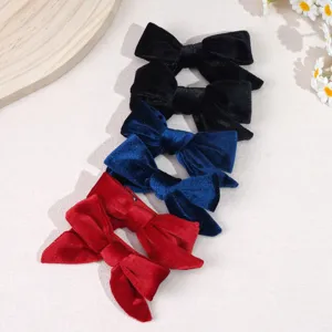 Detailed macro shot of premium velvet bow hair clips in vibrant red, blue, and black.