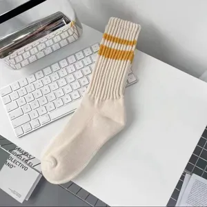 Nahaufnahme von cremefarbenen Socken mit gelben Streifen und weicher Rippenstrick-Textur.