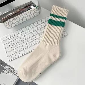 Detailansicht von beigen Crew-Socken im Varsity-Stil mit grünen Streifen auf Tisch