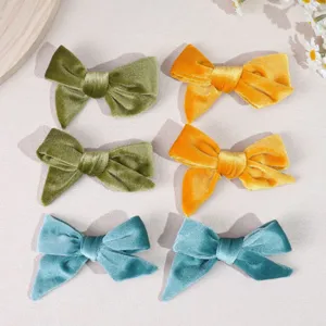 Detailed view of six soft velvet bow hair clips in green, yellow, and blue colors.