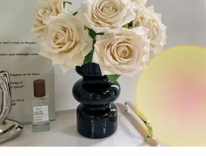 Elegant black ceramic vase with realistic cream white artificial roses in a lifestyle setting.