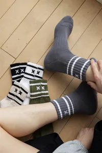 Detailed view of men's mid-tube striped socks with embroidered XX motif and cushioned terry sole.