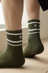 Close-up detail of dark green men's mid-tube socks featuring white stripes and embroidered cross.