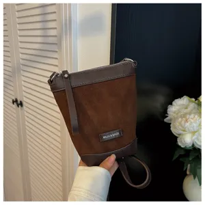 Close-up detail of the brown suede cross-body phone bag showing fine texture and zipper.