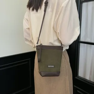 Close-up detail view of a stylish dark green suede and brown leather cross-body phone bag.