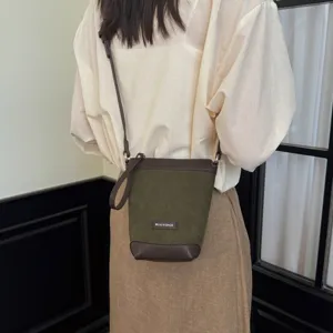 Close-up of green and brown crossbody phone bag with label detail, stylish and versatile.