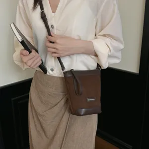 Brown suede crossbody phone bag detail showing texture, strap and small logo label.