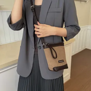 Detail view of the small brown crossbody phone bag with suede texture and shoulder strap.