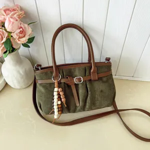 Vista dettagliata di una borsa a tracolla retrò verde con manico marrone e perline di legno.