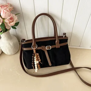 Dettaglio borsa a tracolla casual retrò da donna, camoscio nero e finiture in pelle.
