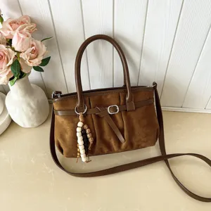 Borsa a tracolla vintage marrone in camoscio dettaglio, con ciondolo di perle e design elegante.