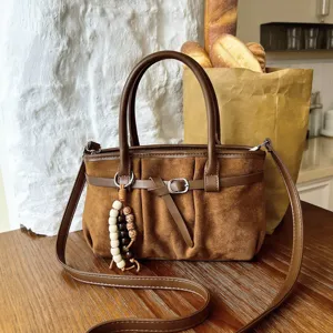 Primo piano della borsa a tracolla in camoscio marrone con ciondolo di perline stile retrò.