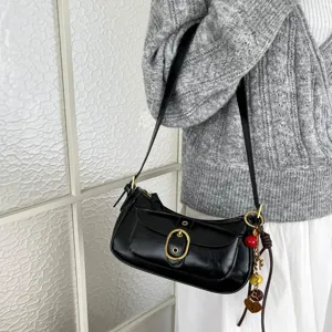 Classic black shoulder bag detail view, featuring metallic gold buckle and chic hanging charms.
