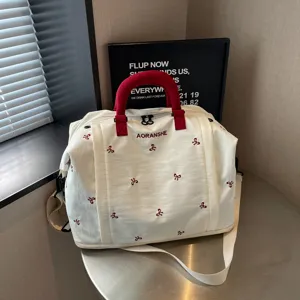 Gran bolsa de viaje duffel con asas rojas y bonito bordado de lazo para viajes cortos.