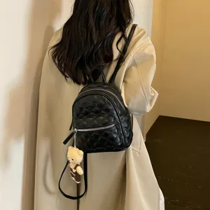 Minimalistische zwarte gewatteerde mini-rugzak voor dames, casual schooltas met berenhanger.