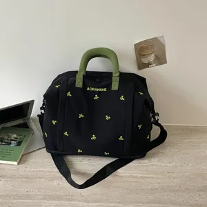 Gran bolsa de viaje negra con asas verdes y bordado de lazos lindos para viajes cortos.