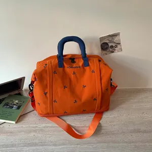 Bolsa de viaje de lona naranja con asas azules y detalles de bordado para deporte y ocio.