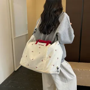 Detalle de bolsa de viaje de lona gran capacidad, bolso fin de semana beige con bordado.