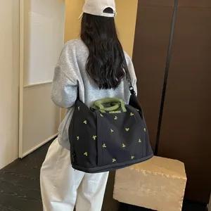 Vista detallada de la gran bolsa de viaje deportiva con asas verdes y un bonito bordado.