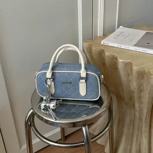 Nahaufnahme Detail der stilvollen gesteppten Jeans-Umhängetasche mit weißem Besatz und Charm.