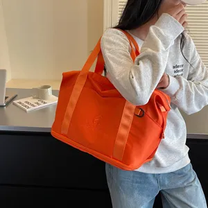 Orange travel duffel bag detail, portable gym fitness tote bag with shoulder strap.