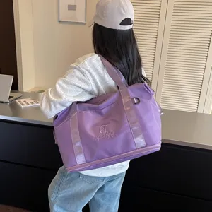 Detail view of the purple travel duffel bag with shoulder strap and front logo display.