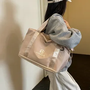 Detail view of the beige travel duffel bag worn on shoulder, showing capacity and fabric texture.