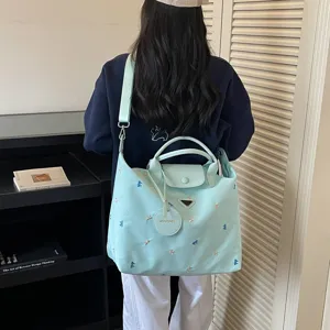 Gedetailleerd uitzicht van de lichtgroene canvas shopper met delicate borduursels.