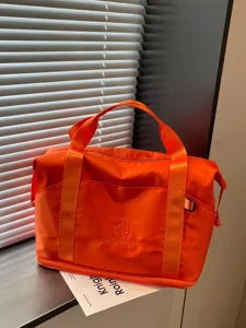 Orange travel duffel bag for women, portable fitness sports gym bag with shoe compartment.